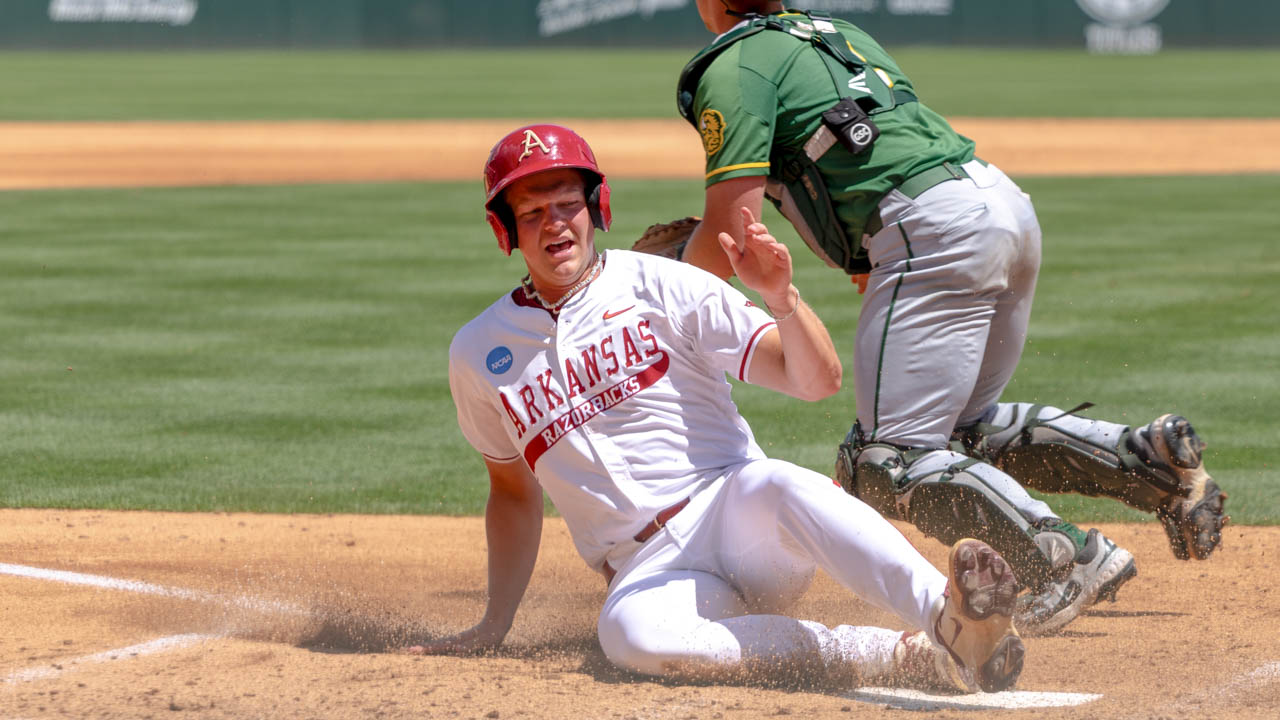 Razorbacks' Cam Kozeal slides across home plate, scoring an early run against North Dakota State