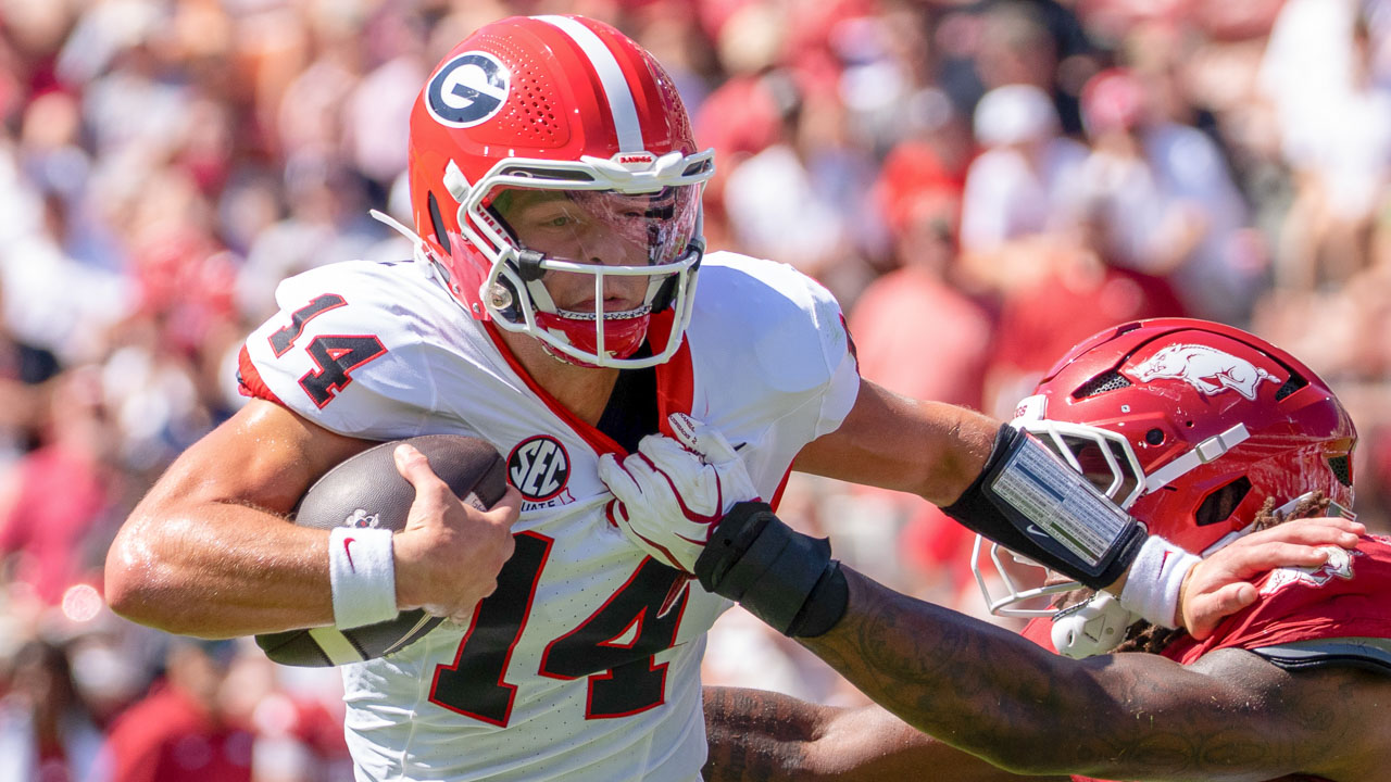 Georgia Bulldogs quarterback Gunner Stockton pushes off an Arkansas Razorback defender in a game at Razorback Stadium